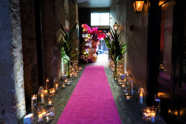 A pink carpet lined with candles representing decor by birthday floral arrangements company The Plant Gallery in Metairie, LA